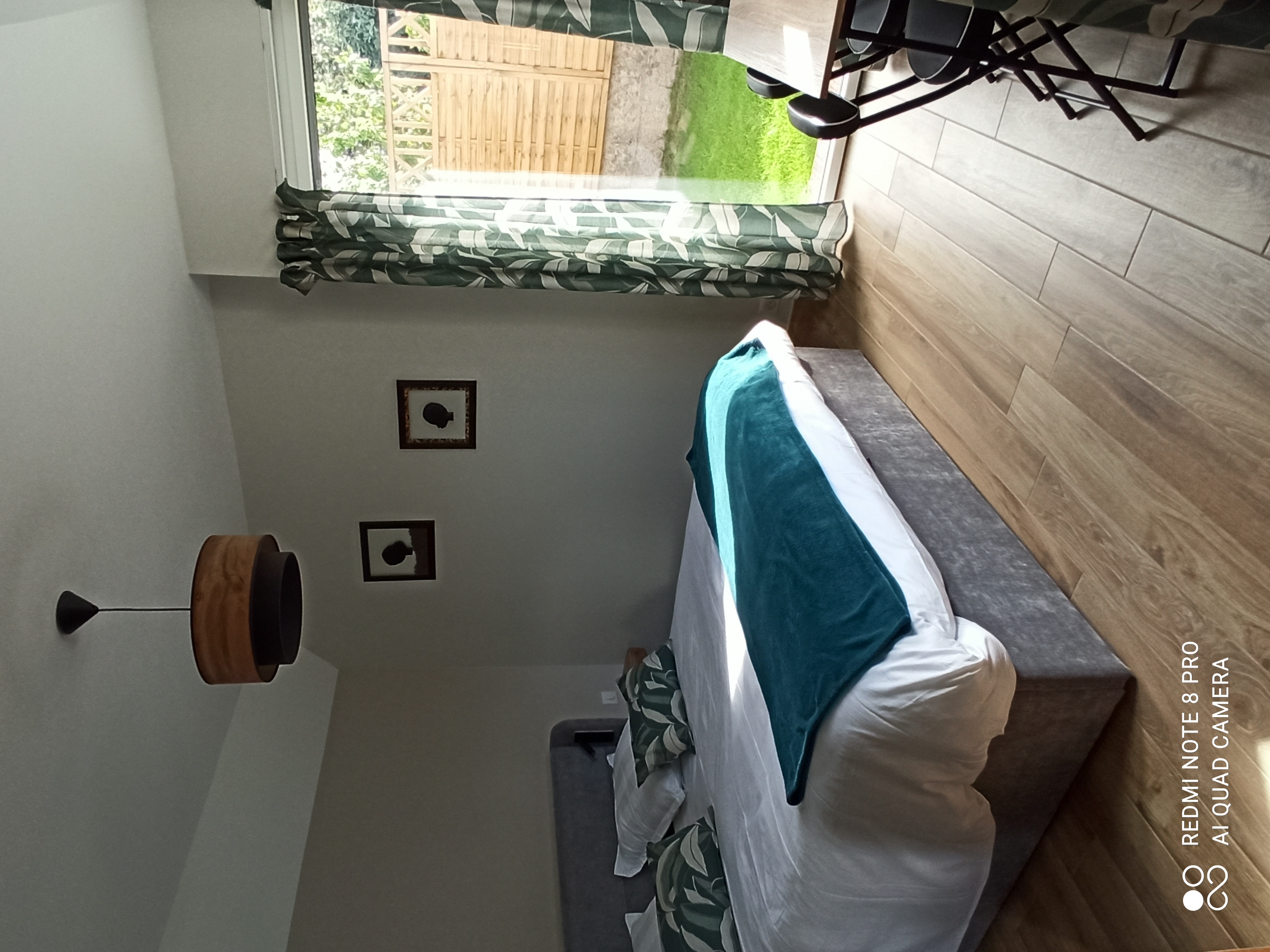 Espace chambre avec lit queen size, rideau vert kaki, porte-fenêtre donnant accès au jardin (Port-Louis, Morbihan, 56