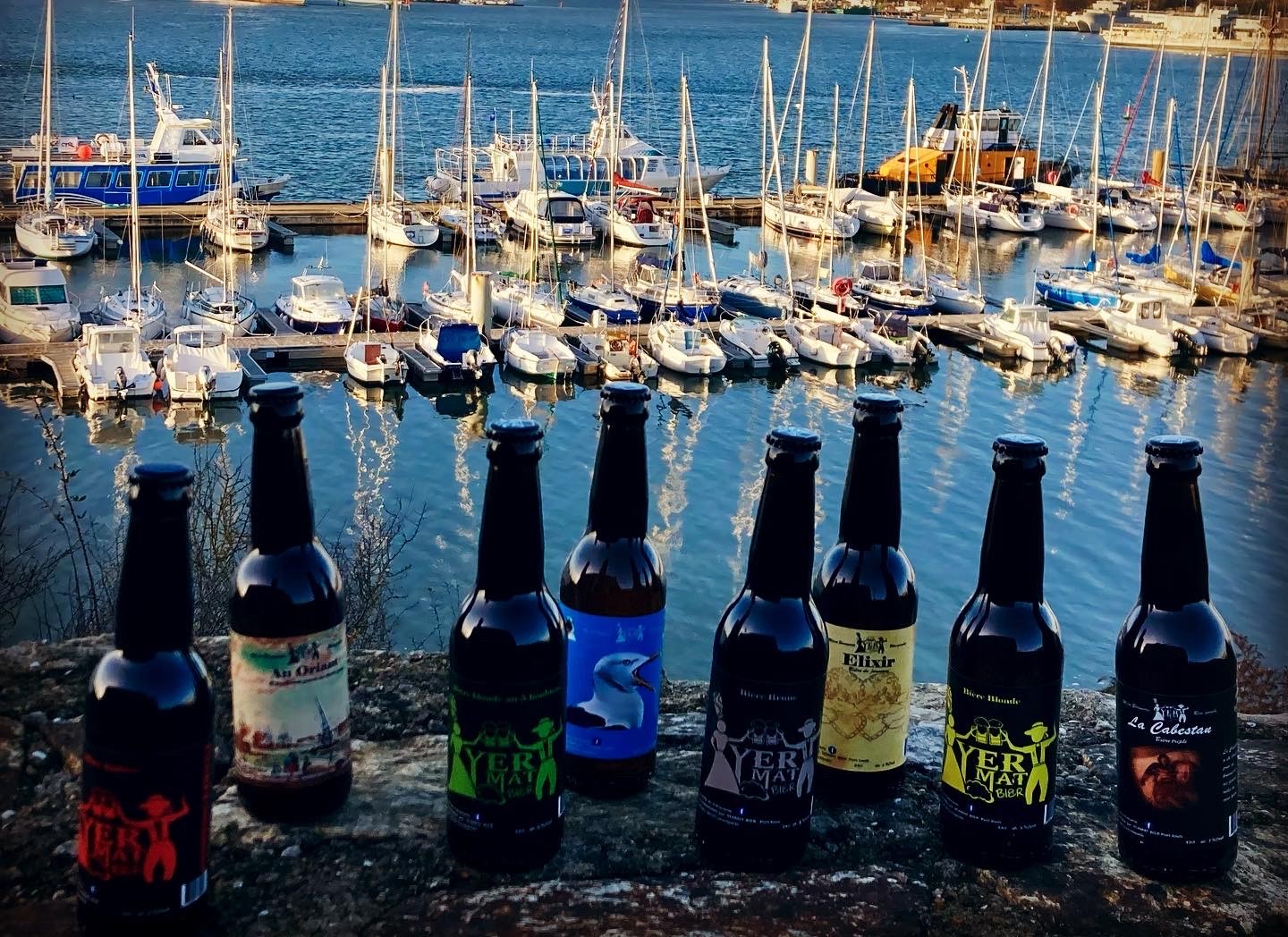 Huit différentes bières produites à la microbrasserie artisanale Yermat, posées devant le port de plaisance de Locmiquélic (Locmiquélic, Morbihan, 56)