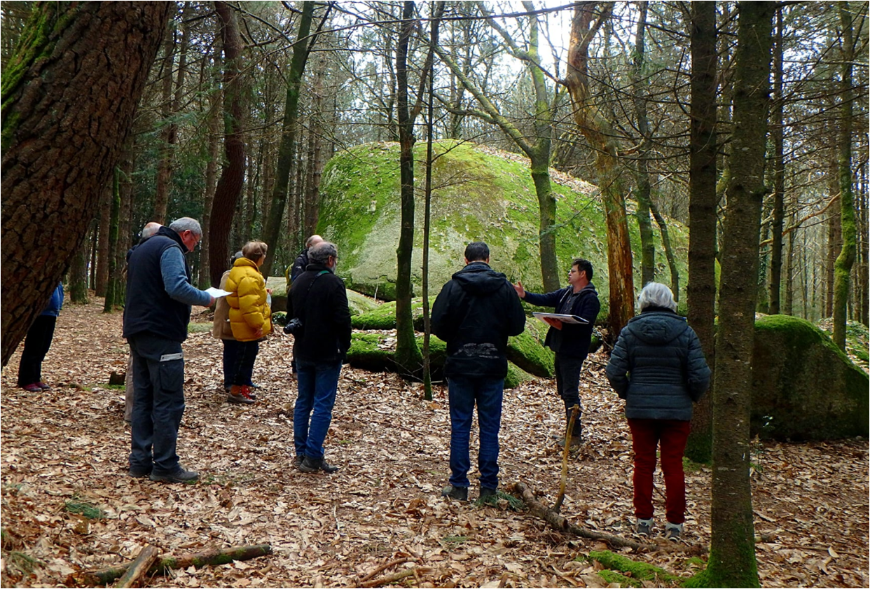 Interaction entre Samuel Piriou, le Géologue Ambulant, et un groupe de participants au cœur des landes de Lanvaux, devant un mégalithe (Plouhinec, Morbihan, 56)