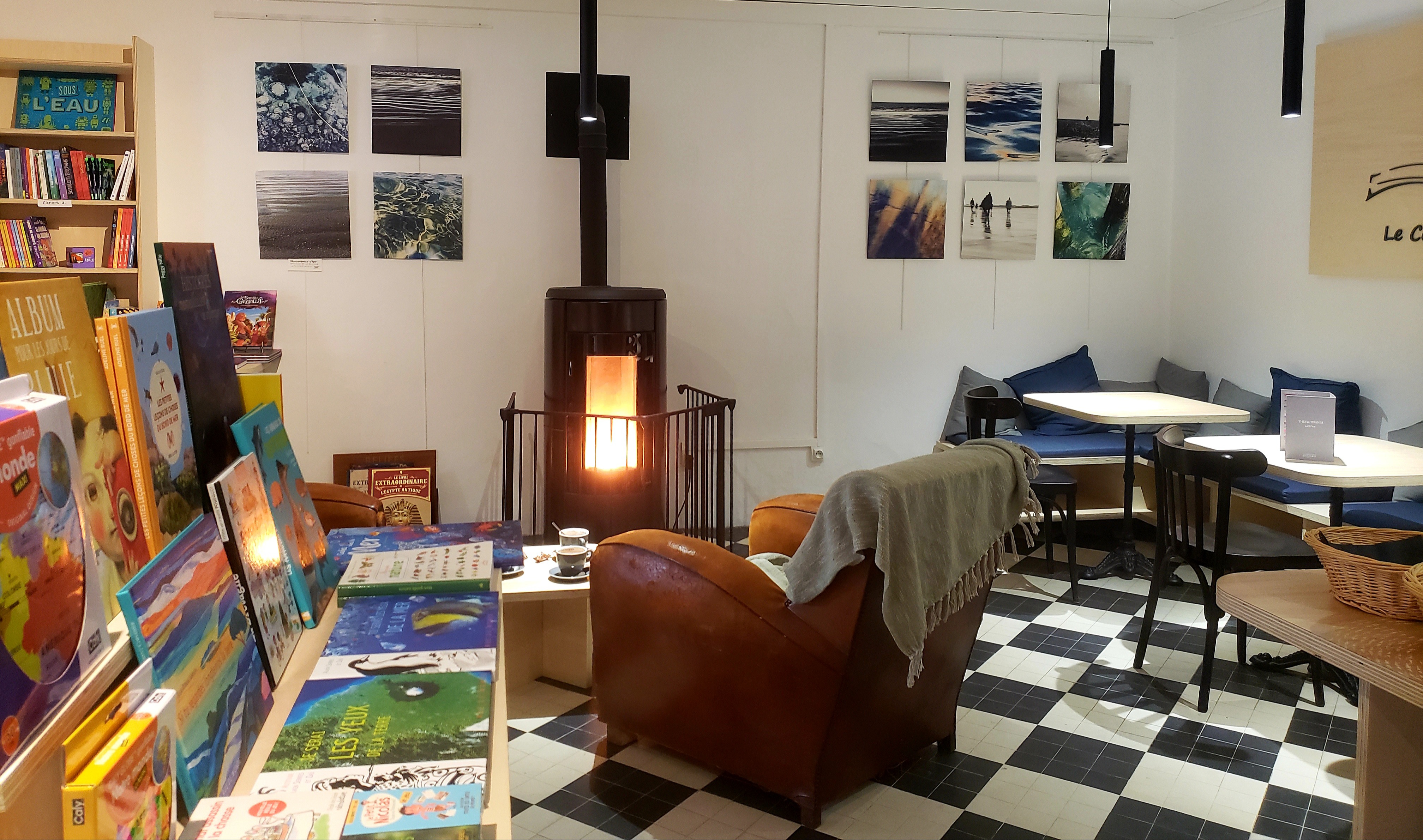 Intérieur cozy du Comptoir Gâvrais, carrelage noir et blanc, coin lecture auprès du poêle (Gâvres, Morbihan, 56)