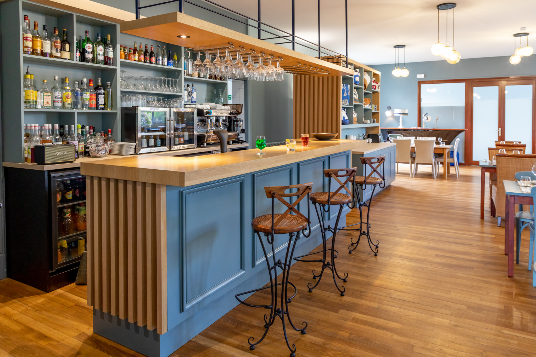 L'espace bar de l'hôtel, parquet, comptoir en bois et peinture bleue, tabourets de bar en bois avec dossier design industriel (Port-Louis, Morbihan, 56)