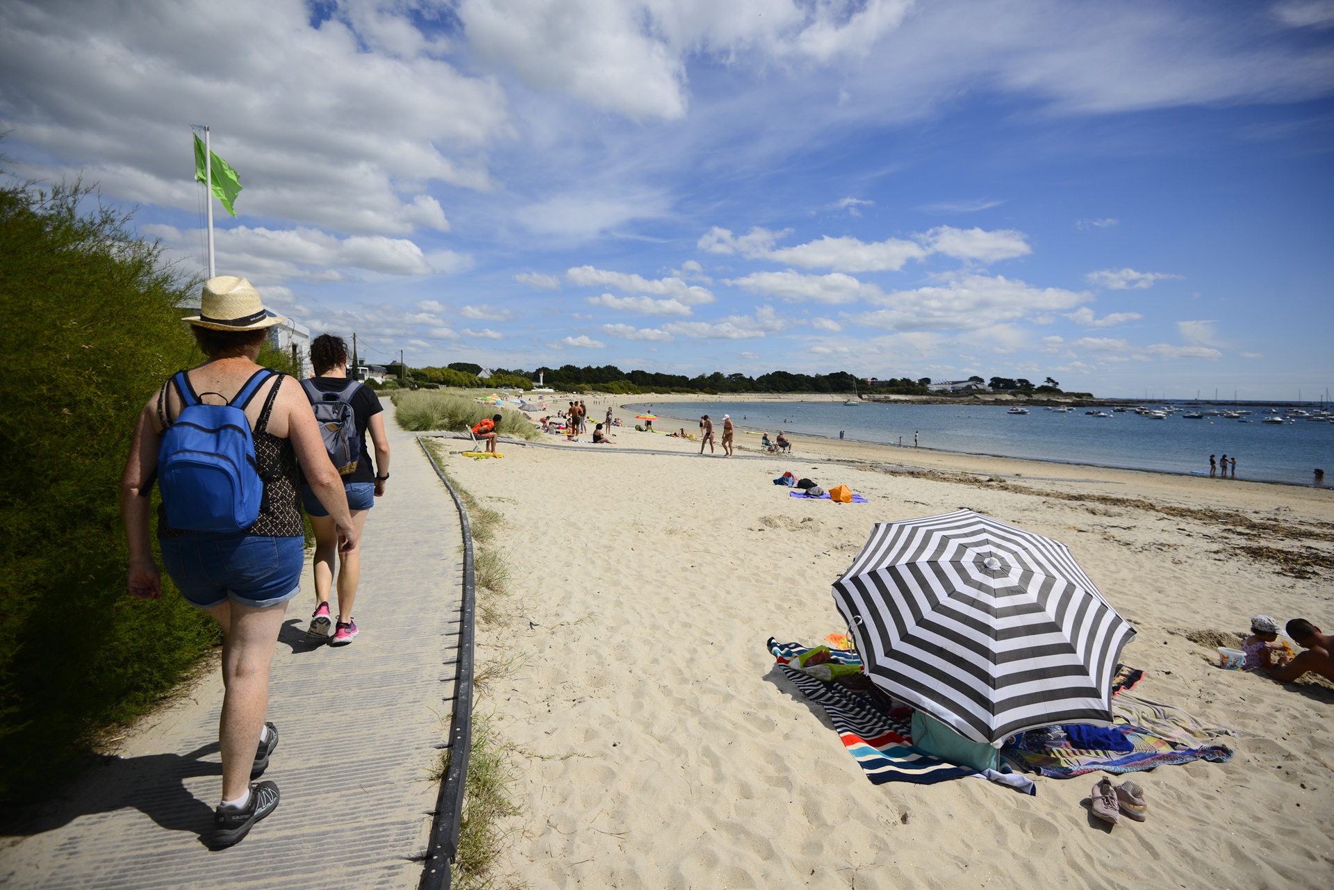 Promeneurs sur la palissage qui longe la plage de l'anse du Stole à Ploemeur (Morbihan) 56