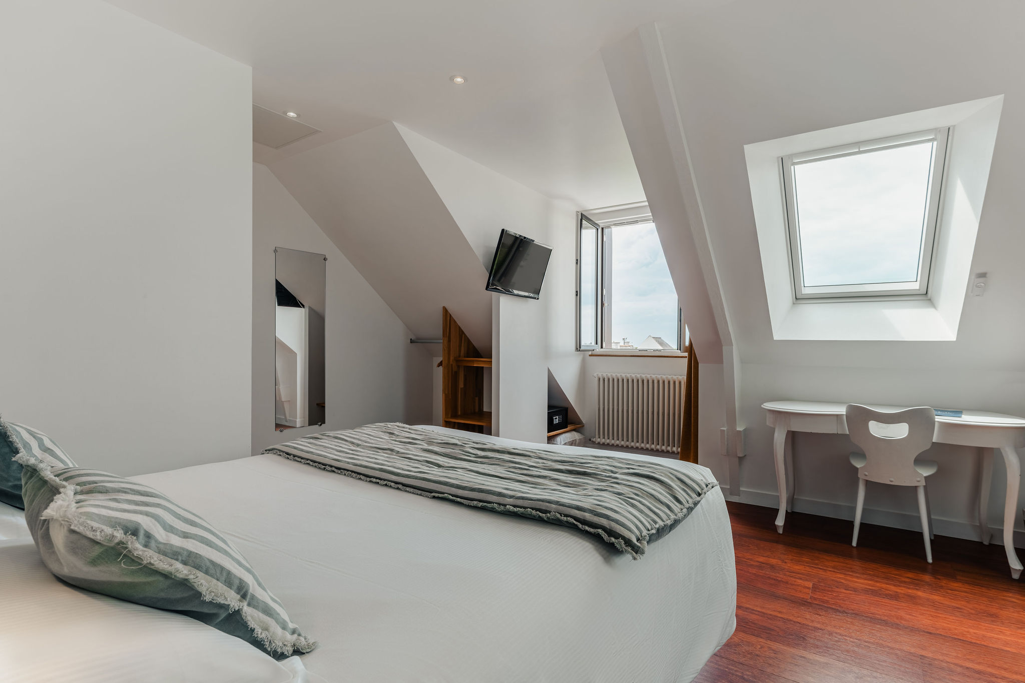 Une chambre de l’hôtel avec parquet, sous plafond mansardé, tons blancs (Port-Louis, Morbihan, 56)