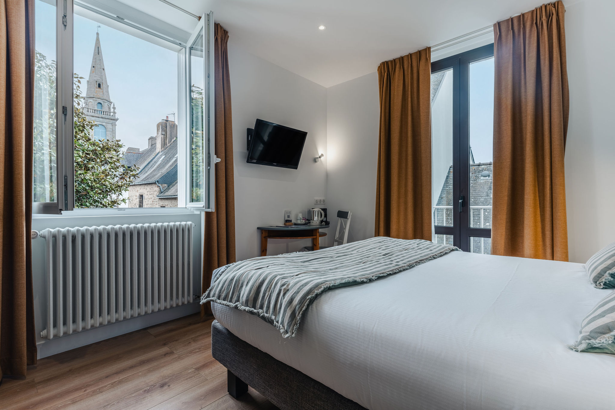 Une chambre de l’hôtel avec vue sur le clocher de Port-Louis, parquet, lit double, décoration marine rayée et papier peint vagues (Port-Louis, Morbihan, 56)