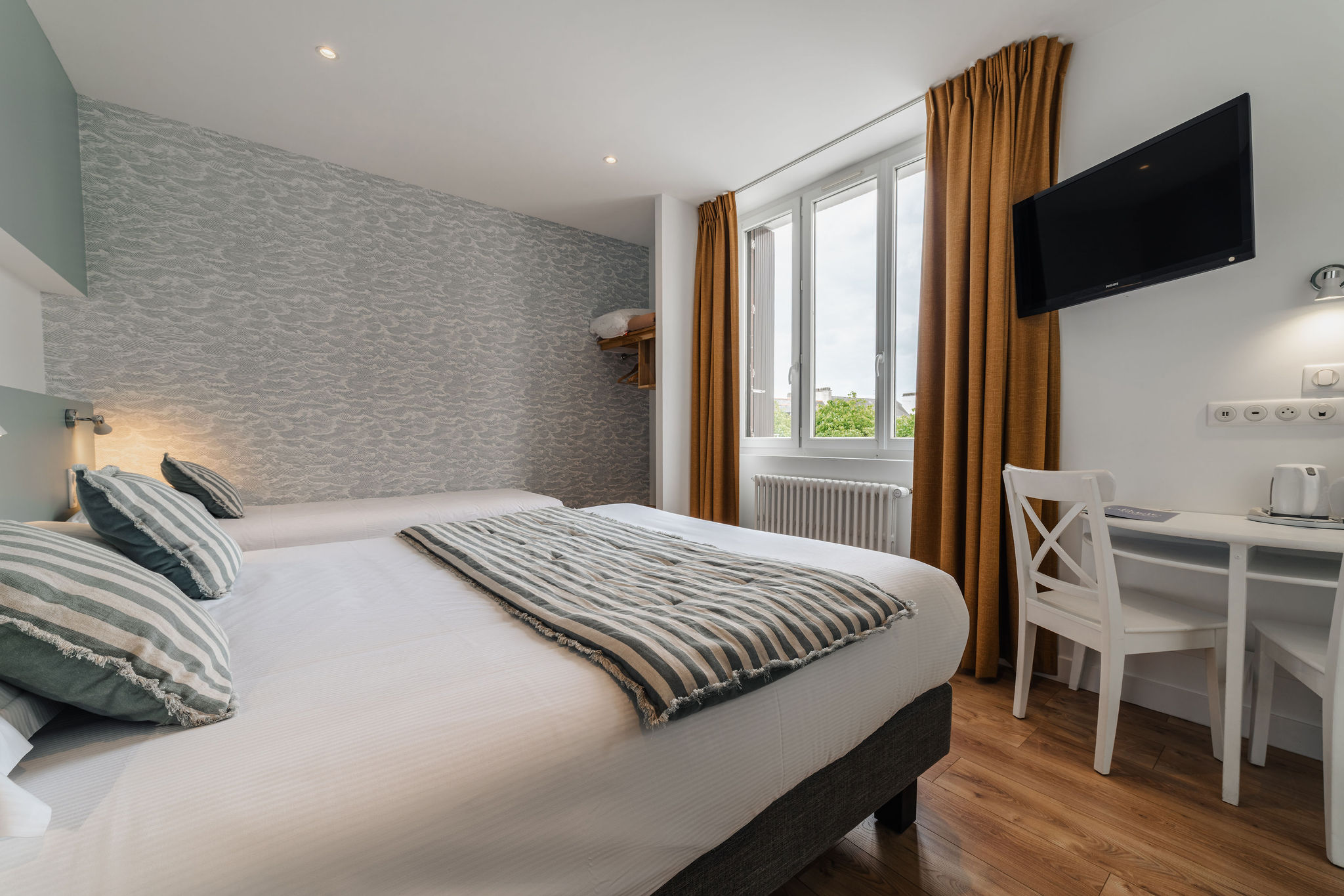 Une chambre de l’hôtel, parquet, lit double, décoration marine rayée et papier peint vagues (Port-Louis, Morbihan, 56)