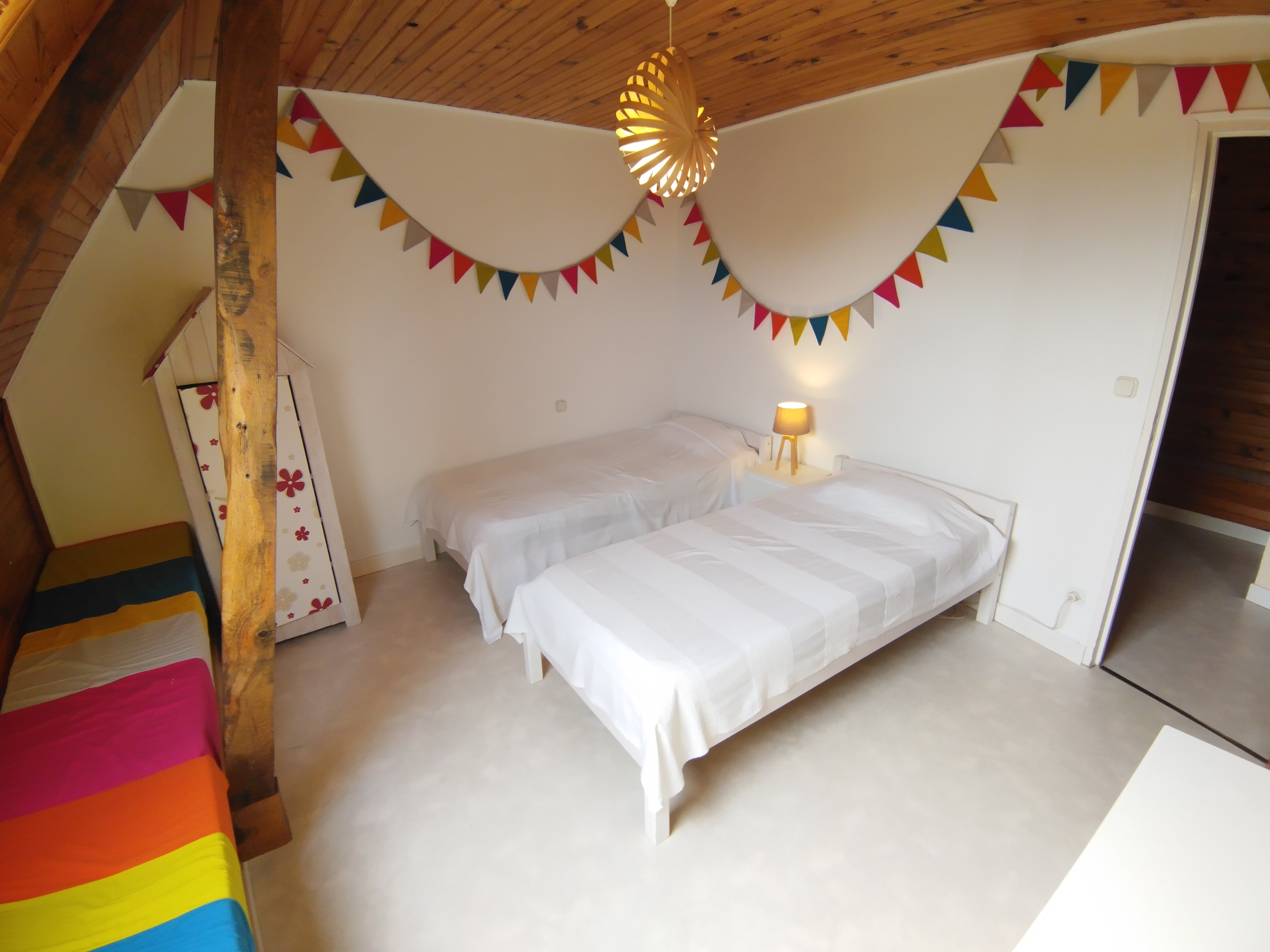 Chambre avec deux lits simples, murs aux tons blancs et décoration colorée, fanion et suspension en paille tressée (Sainte-Hélène, Morbihan, 56)