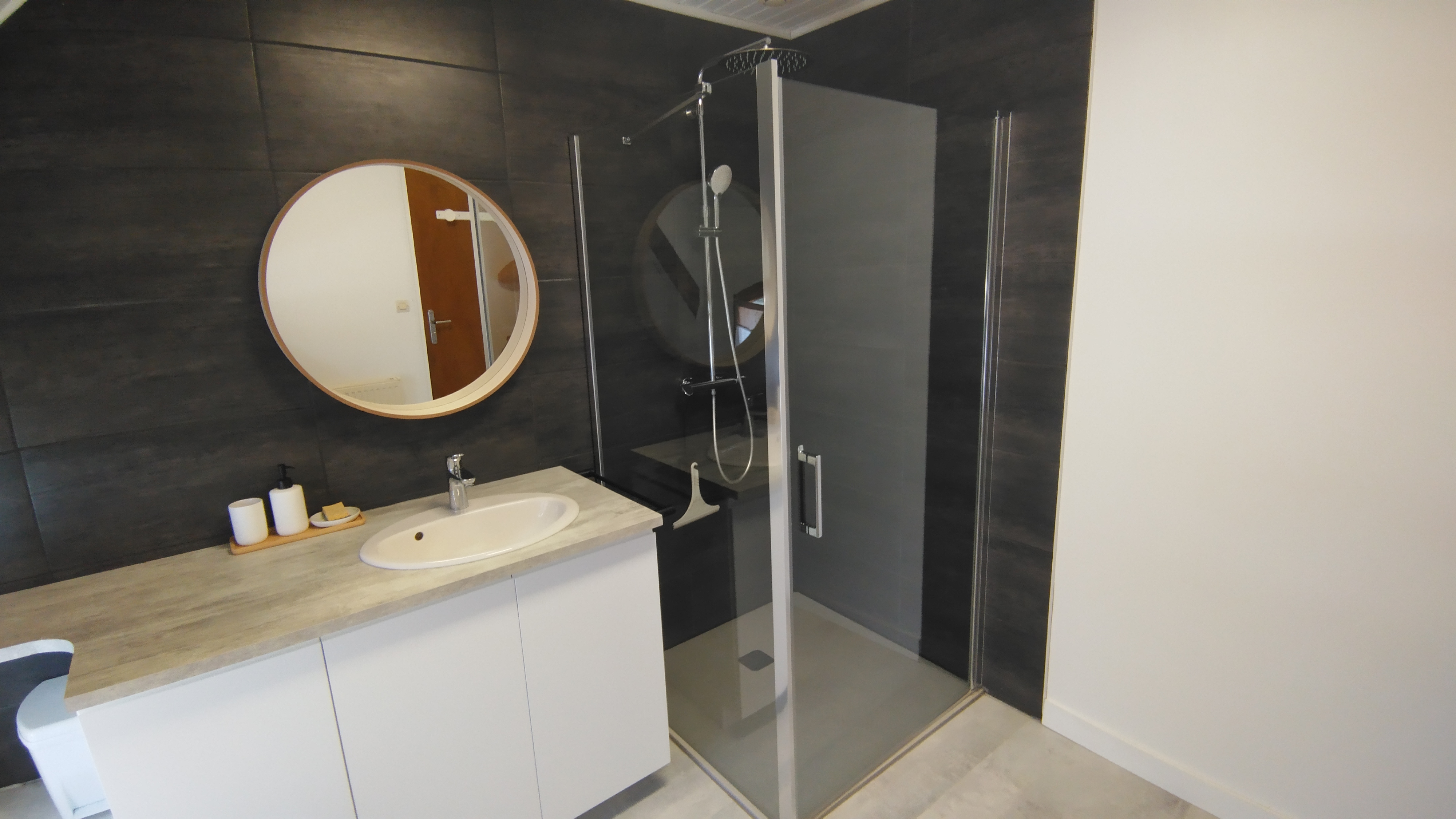 Plan serré sur la salle-de-bain avec cabine de douche et lavabo, carrelage gris foncé (Sainte-Hélène, Morbihan, 56)