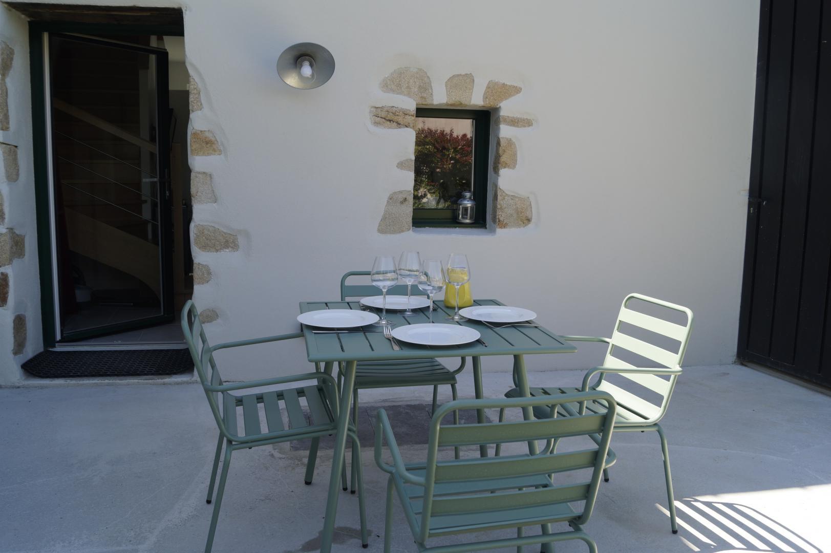 Vue sur la terrasse extérieure avec petite table et chaises de jardin en métal (Sainte-Hélène, Morbihan, 56)